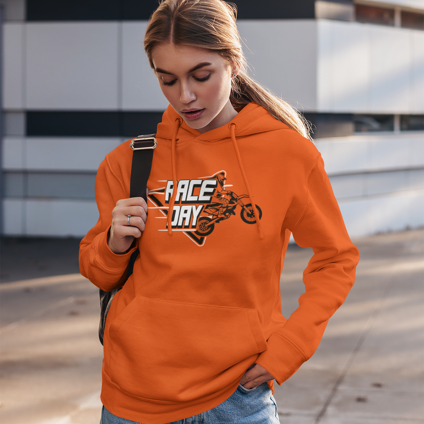 Person wearing an orange hoodie with a graphic design, standing outdoors.