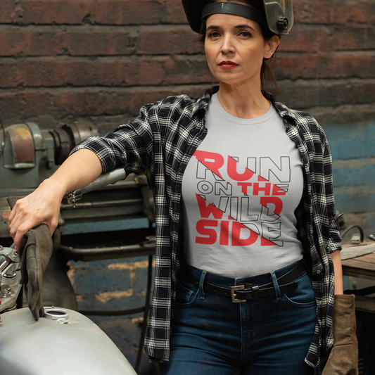 Woman wearing a t-shirt with text standing next to a motorcycle in an industrial setting
