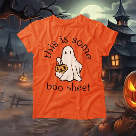 Orange t-shirt with ghost and pumpkin design on a Halloween-themed background with pumpkins and a haunted house.
