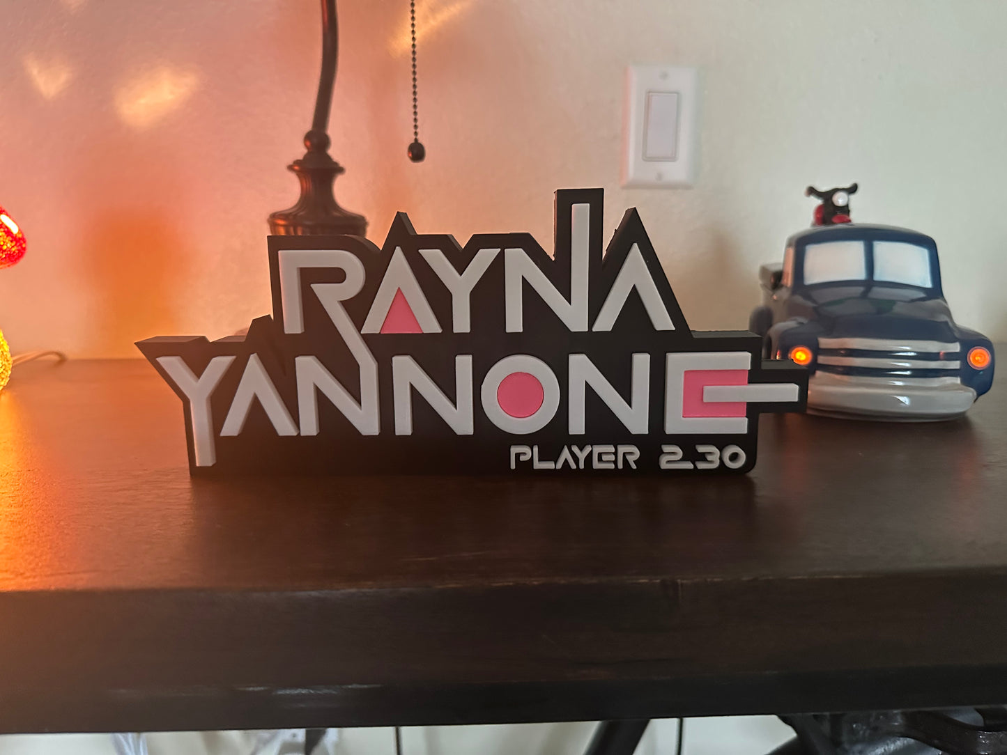 Wooden nameplate with 'Rayna Yannone' and 'Player 2.30' on a table.