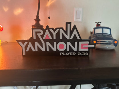 Wooden nameplate with 'Rayna Yannone' and 'Player 2.30' on a table.