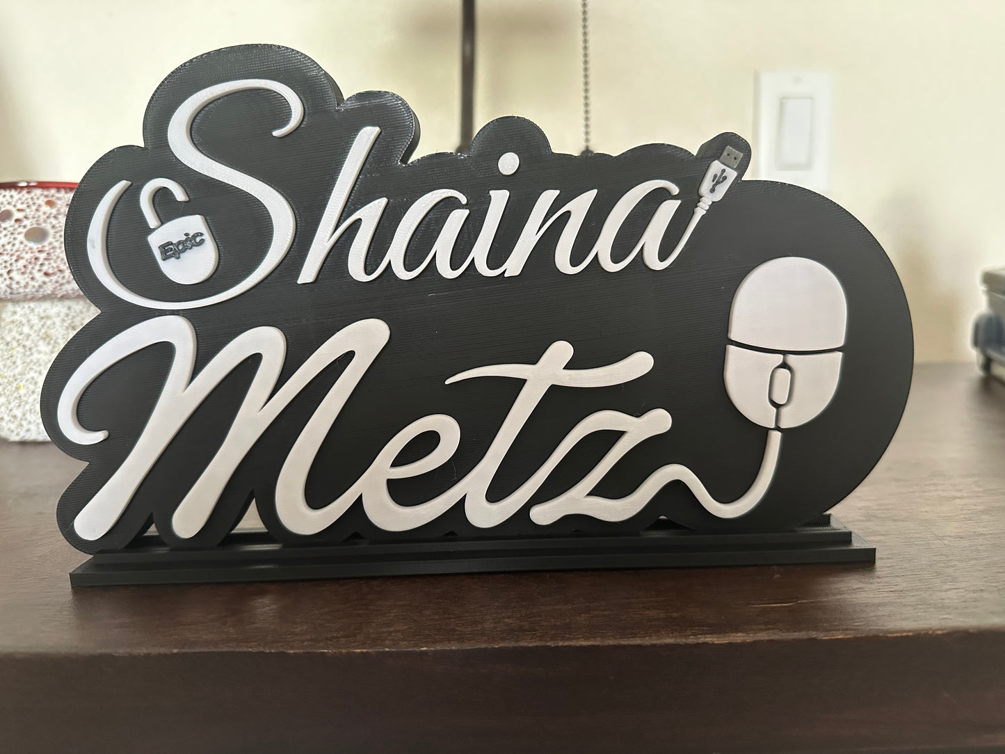 Decorative sign with 'Shaina Metz' on a wooden surface