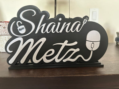 Decorative sign with 'Shaina Metz' on a wooden surface