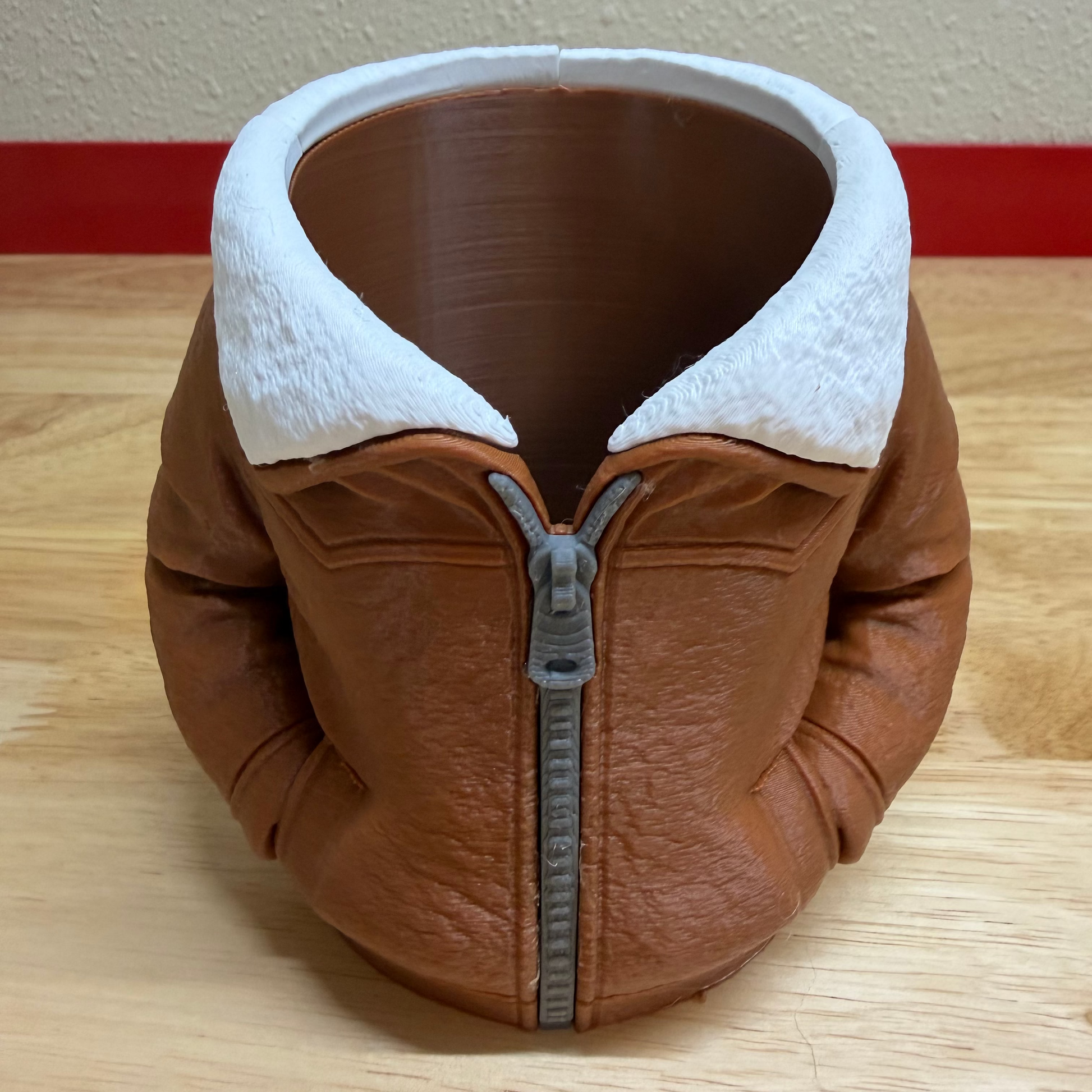 Brown leather jacket with white lining on a wooden surface