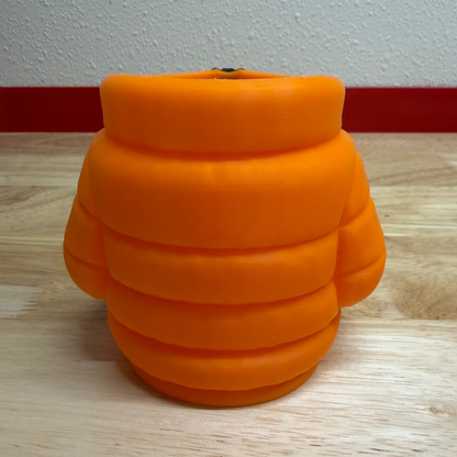 Orange plush toy resembling a bee on a wooden surface with a white wall background