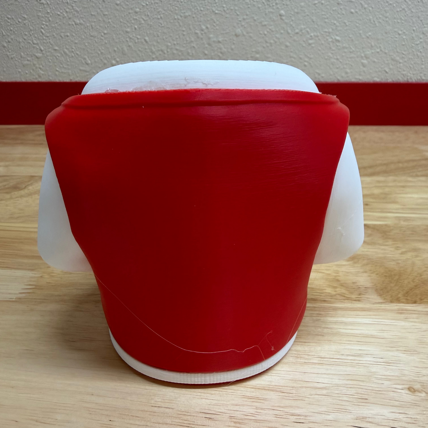 Red and white container on a wooden floor with a white wall background