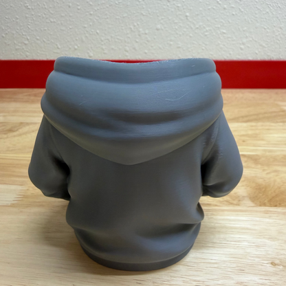 Gray hoodie on a wooden floor with a white wall and red baseboard in the background