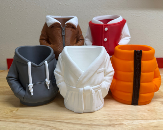 Four colorful mug-shaped objects resembling jackets on a wooden surface.
