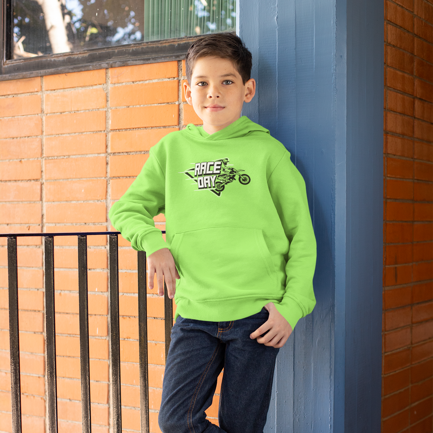 Child wearing a bright green hoodie with text and graphics, standing against a blue wall.