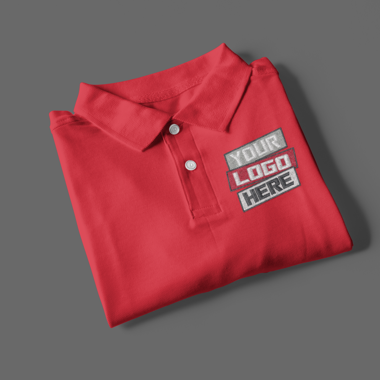 Folded red polo shirt with customizable logo patch on a gray background