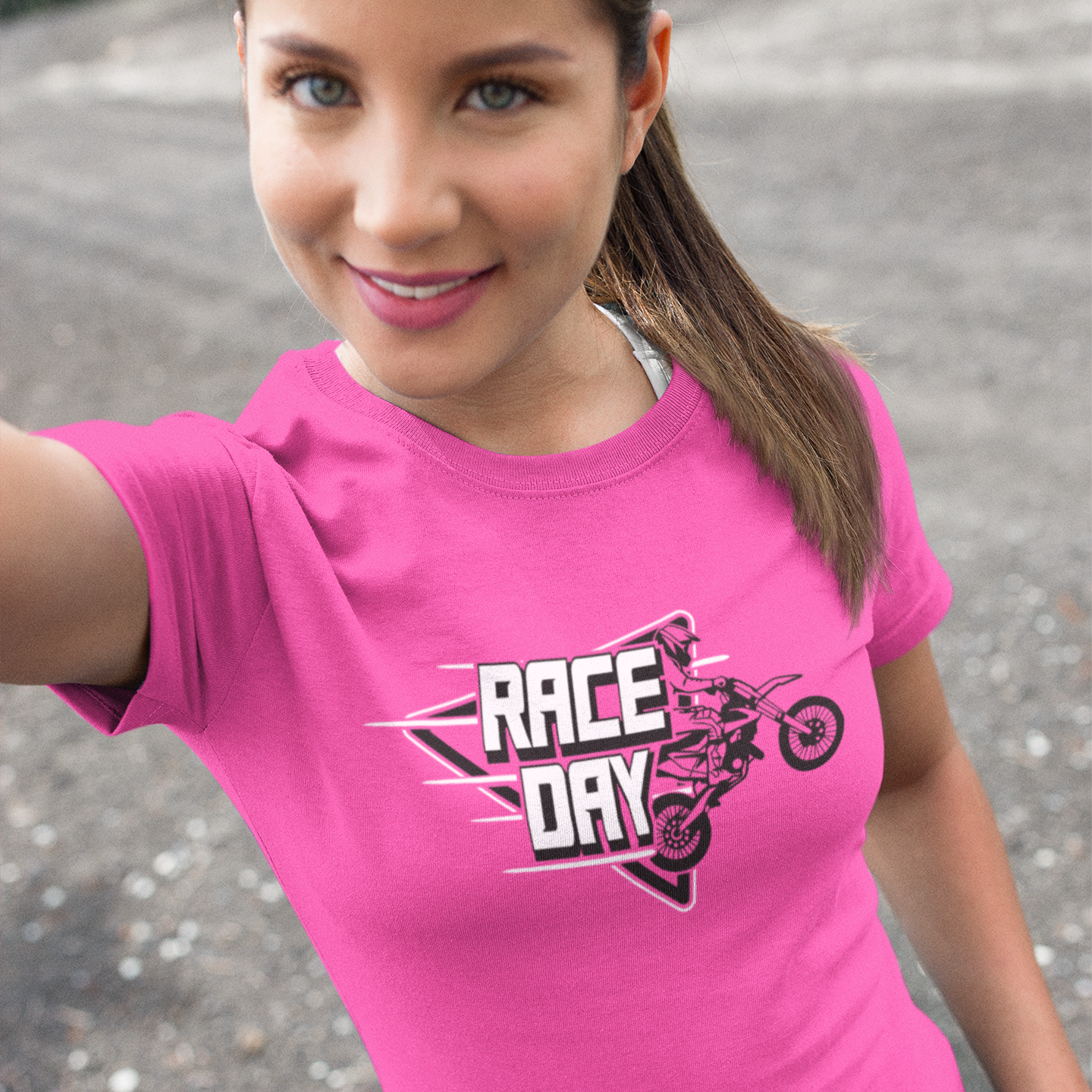 Woman wearing a pink 'Race Day' t-shirt with a graphic design outdoors.