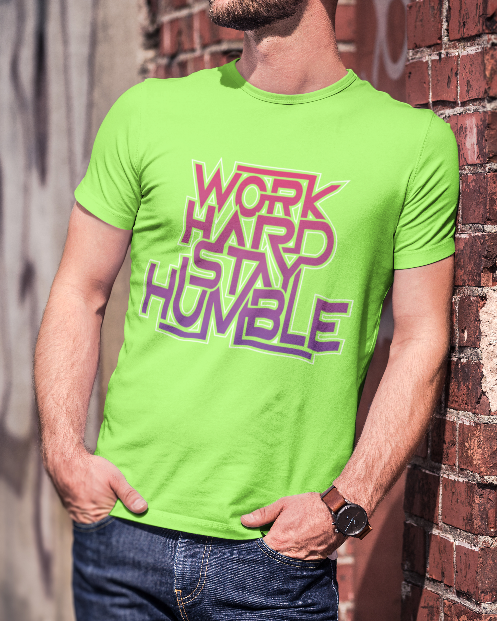 Person wearing a bright green t-shirt with 'Work Hard Stay Humble' text against a brick wall.